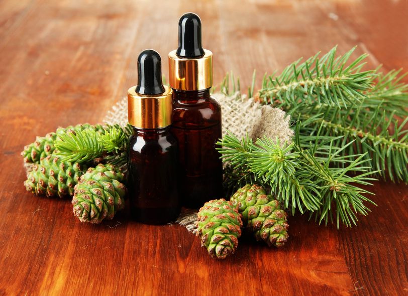 Oil bottles on a wooden table nestled in fir cones