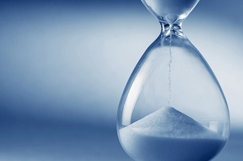Closeup hourglass clock on light blue background