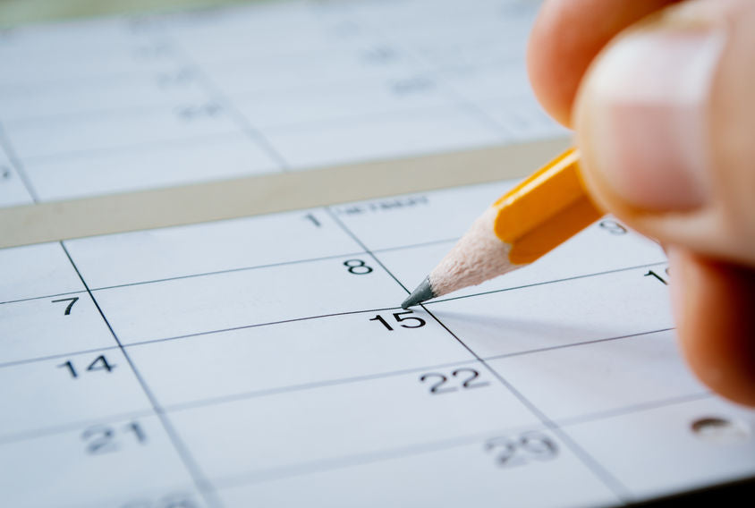Massage therapist marking the date of the 15th with a pencil on a blank calendar with date squares as a reminder of an important day or to schedule an appointment