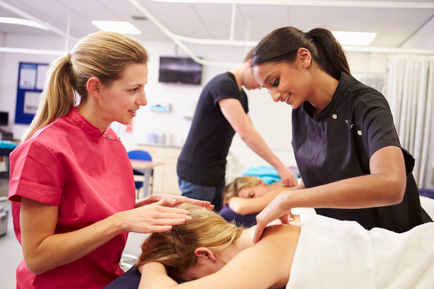 Teacher Helping Student Training To Become Massage Therapist