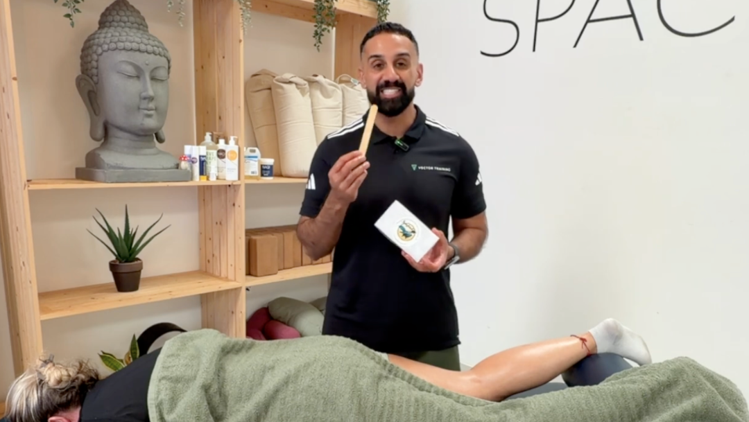 A sports therapist holding up a wooden wax spatula alongside its box packaging, ordered from Massage Warehouse, premier supplier for professional therapists in the UK and Ireland; highlights the single-use disposable design for easy wax portioning and maintaining strict clinical sanitation standards in Aberdeen.